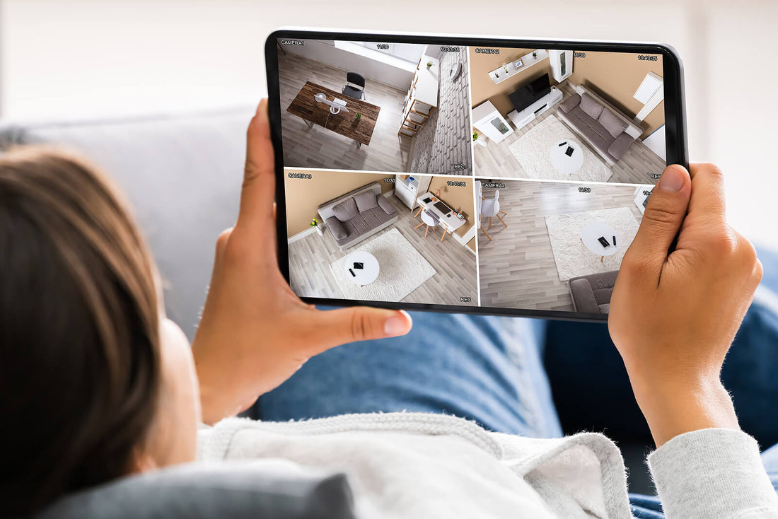 Person using a tablet to monitor a home security system with multiple camera views, showcasing the convenience and real-time monitoring capabilities of smart surveillance technology.